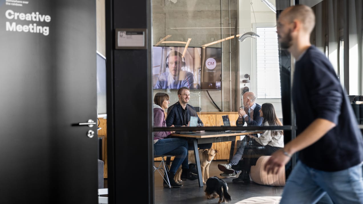 Jemand läuft am Creative Meeting Room vorbei, wo gerade ein Meeting stattfindet